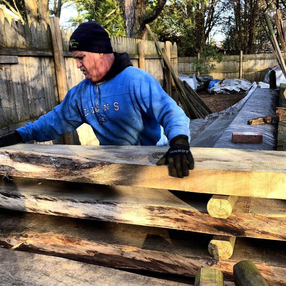 Jim is placing a newly sawn live edge slab on the top of the stack of slabs